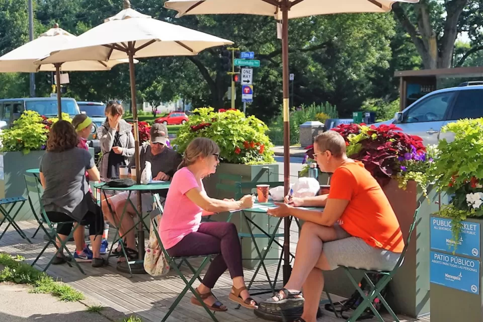 People sitting at small tables in a public parklet in Minneapolis, Minnesota.